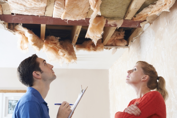 A home inspector and potential home buyer look at damage in the home’s ceiling.